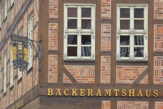 Nose plate with golden year on a brick house, half-timbered house, house facade, window, wrought