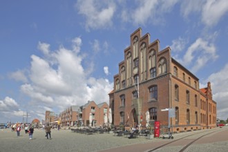 Brick building with stepped gable at the harbour and pedestrians, tourists, houses, stepped gable,