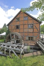 Grinding mill with brick building and water wheel, mill wheel, wooden construction, inscription,