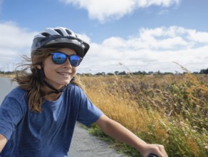 A girl with a bicycle helmet rides on a bicycle and smiles friendly, AI generated, AI generated