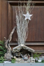 Detailed nativity scene scene with wood and decorative star, surrounded by natural elements,