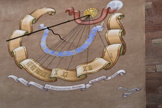 Artfully painted sundial on a sandstone wall with Roman numerals and decorative elements, Alsace,