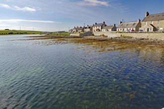 Quiet coastal village with houses along the water and blue sky in the background
