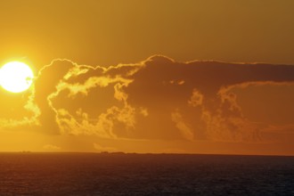 Sunset over the sea with bright sun and dramatic clouds, crossing between Orkney and Shetland