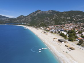 Aerial view of a long sandy beach with neighbouring town and mountainous background, aerial view,