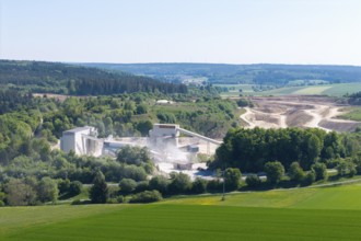 A large industrial plant embedded in a hilly, green landscape, gravel works near Böhmenkirch,