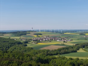 A small village surrounded by fields and wind turbines on green hills, near Böhmenkirch, Swabian