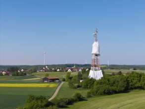 Landscape with transmission tower and many wind turbines surrounded by fields, radio tower being