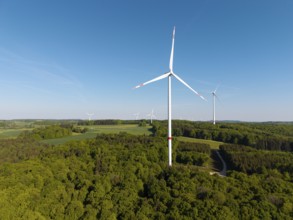 Single wind turbine in the middle of forest and fields under a clear sky, near Westerheim, Swabian