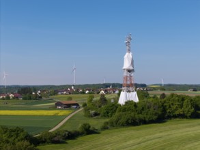 A transmission tower and wind turbines near a village under a blue sky, radio tower being