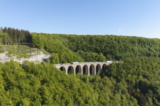 A viaduct leads over a dense forest landscape under a blue sky, Drachenloch bridge on the
