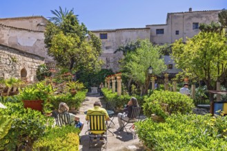 People sitting on chairs and enjoying the sun in the botanical garden at The Arab baths in Palma,
