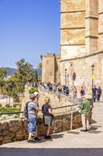 Tourists by a wall outside the Palma Cathedral a sunny summer day, Palma de Mallorca, Mallorca,