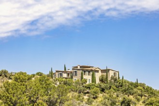 House on a hill with lush green trees and a sunny blue sky in the summer, Mallorca, Spain