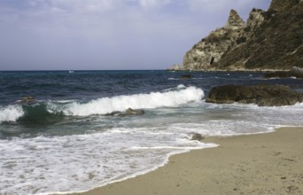 Waves rolling over the sandy beach, rocky coast in the distance, Ricadi, Capo Vaticano