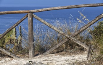 Rustic wooden fence overlooking the blue sea and coastal vegetation, Ricadi, Capo Vaticano