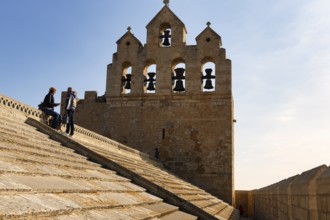 Bell tower of Notre-Dame-de-la-Mer church, two tourists enjoying the view from the roof of the