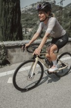 Young woman riding a racing bike on Lake Garda. Sunny weather and dolce vita