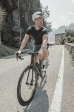 Young man riding a racing bike on Lake Garda. Sunny weather and dolce vita