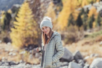 Woman in winter clothes in autumn Engadine with golden trees in Switzerland