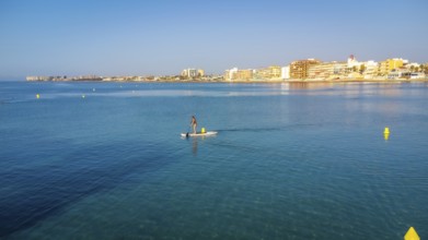 Calm waters and clear skies set the scene for a serene paddle boarding experience near a coastal