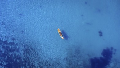 Aerial view of a sportswoman paddle surfing on a sup board in the transparent waters of the ocean