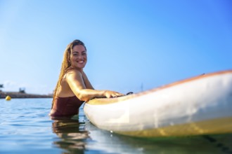 Woman enjoying paddle surfing in clear blue water, showcasing a joyful summer experience under a