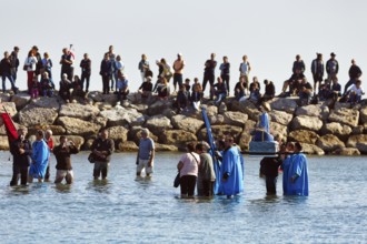 Crowd during pilgrimage, procession by the sea, pilgrims walking through water, statue of the