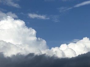 At the bottom of the picture grey nimbostratus clouds, above white cumulus cumulus clouds in front