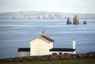 White house overlooking the calm sea and distant cliffs on the horizon, Hillswick, Eshaness,