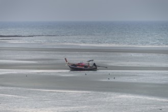 Before sunrise, a lonely longtail boat lies at low tide in the harbour at Sivalai Beach, Koh Mook