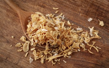 Smoked onion flakes, on a wooden spoon, wooden table, close-up