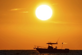 The sun rises behind a boat on the Costa Rei, a coastal section of the Italian Mediterranean island