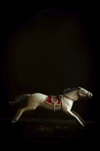 A vintage toy horse captures a galloping stance, emphasizing the intricate craftsmanship of its