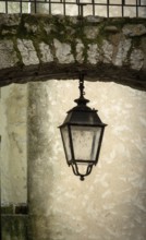 Sisteron. A hanging lantern is positioned beneath an archway made of weathered stone.