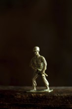 A small soldier figurine poses with determination against a dark, blurred background