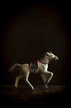 A vintage toy horse trots gracefully across a soft, warm background, highlighting its intricate