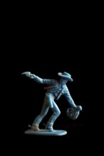 A vibrant blue cowboy action figure strikes a dramatic pose while drawing a weapon, set against a