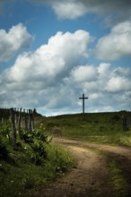 A winding dirt road leads the eye to a solitary cross. Cézallier, Auvergne Volcanoes Regional