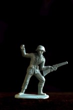 A plastic soldier figurine stands confidently with a rifle and raised fist, captured in warm