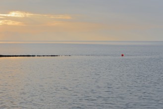 Evening mood at the Wadden Sea, stone groyne with red buoy, North Sea, Norddeich, Lower Saxony,