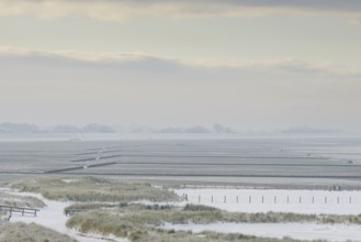 View over the snow-covered dune landscape of Norddeich, Wadden Sea at low tide, North Sea, Lower