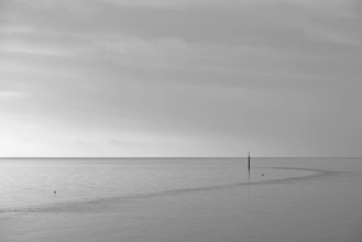 Wadden Sea at rising water, stone groyne with sea mark, black and white, North Sea, Norddeich,