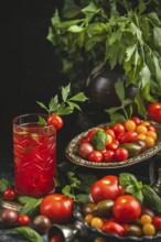 Rustic still life with tomatoes, tomato juice and herbs in a dark setting