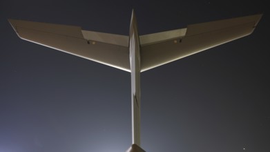 Close-up view of an airplane tail and wings against a clear twilight sky, captured from behind