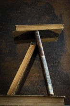 A vintage book stand showcases several old books in a unique position, highlighting their worn