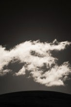 Fluffy clouds float gracefully across a darkening sky, illuminated softly by fading daylight,