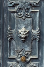 A striking door features detailed carvings and a lion head knocker, blending antique charm with