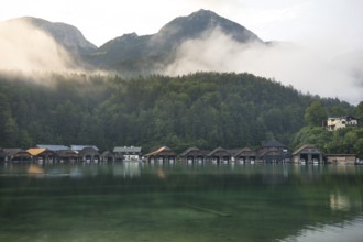 Mystical morning at Königssee in Schönau with boathouses. Sunrise and beautiful wafts of mist over