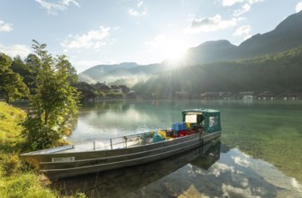 Beautiful morning at the Königssee in Schönau with a boat and boathouses in the background. Sunrise